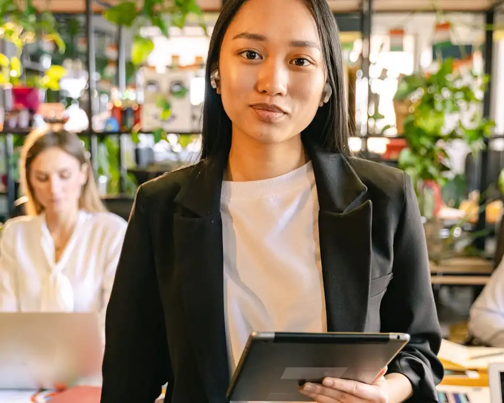 A business woman looks at the camera with a tablet in hand