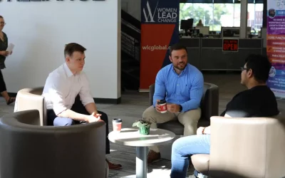 Three young professionals sit on chairs and discuss things