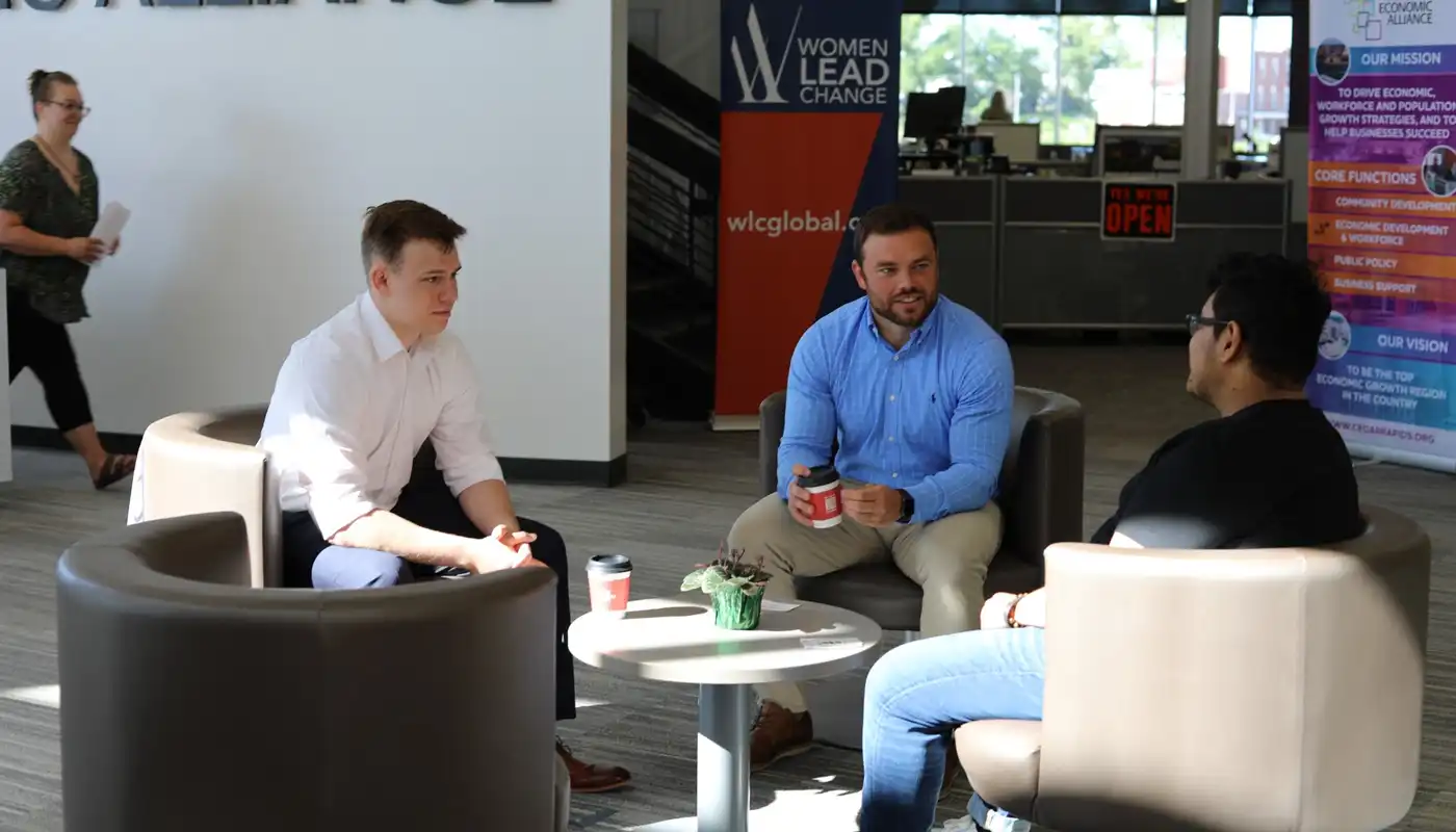 Three young professionals sit on chairs and discuss things