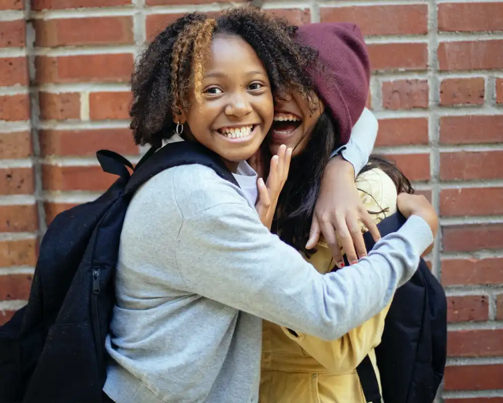 Two young women embrace and smile