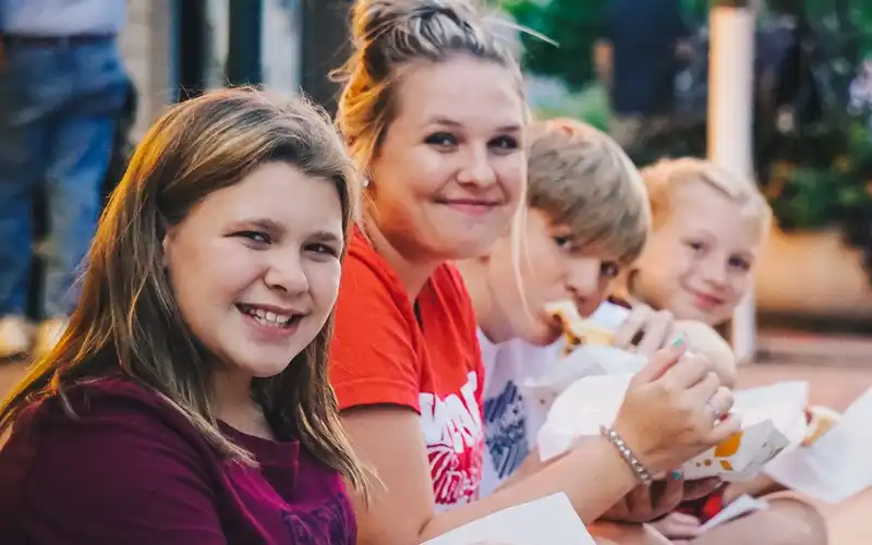 A group of youth sit on a curb and enjoy snacks