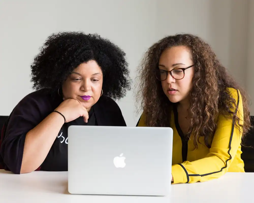 Two people look at a laptop computer