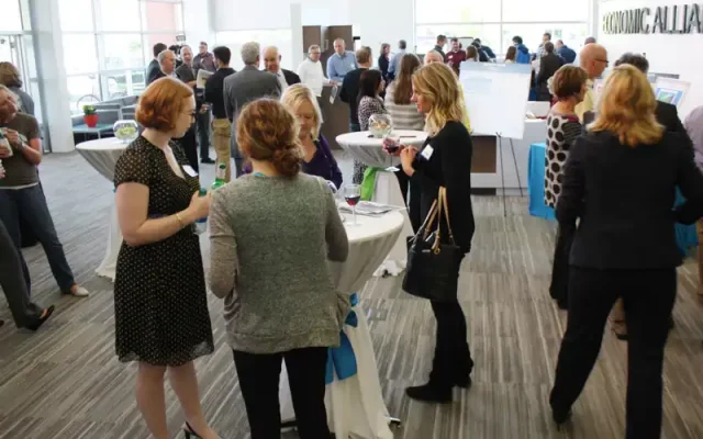 A group of business people mingle in a large lobby