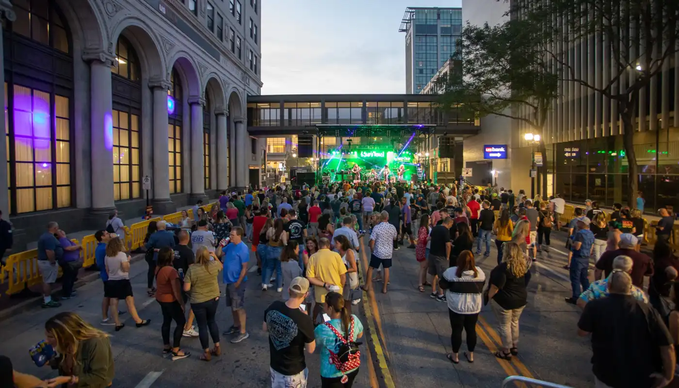 A crowd gathers in a street to watch a band