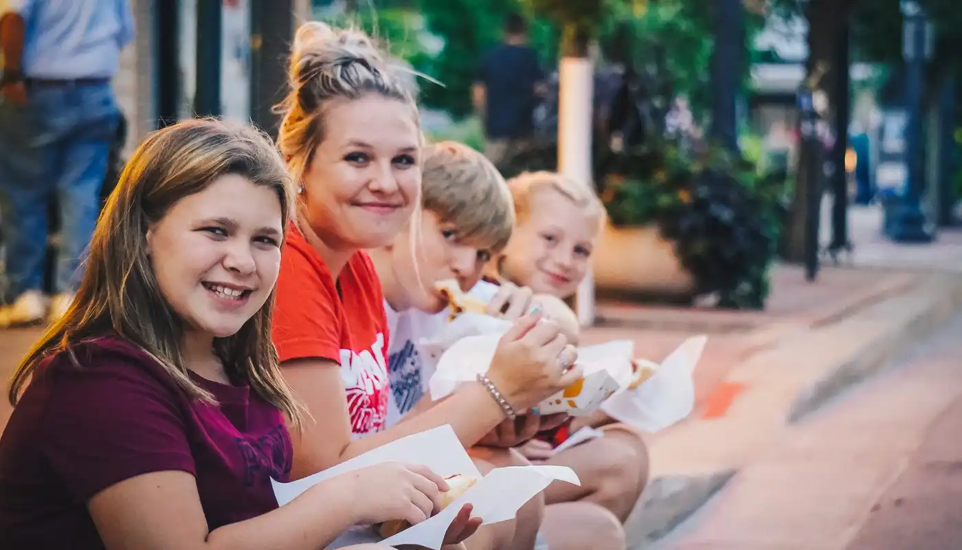 A group of youth sit on a curb and enjoy snacks