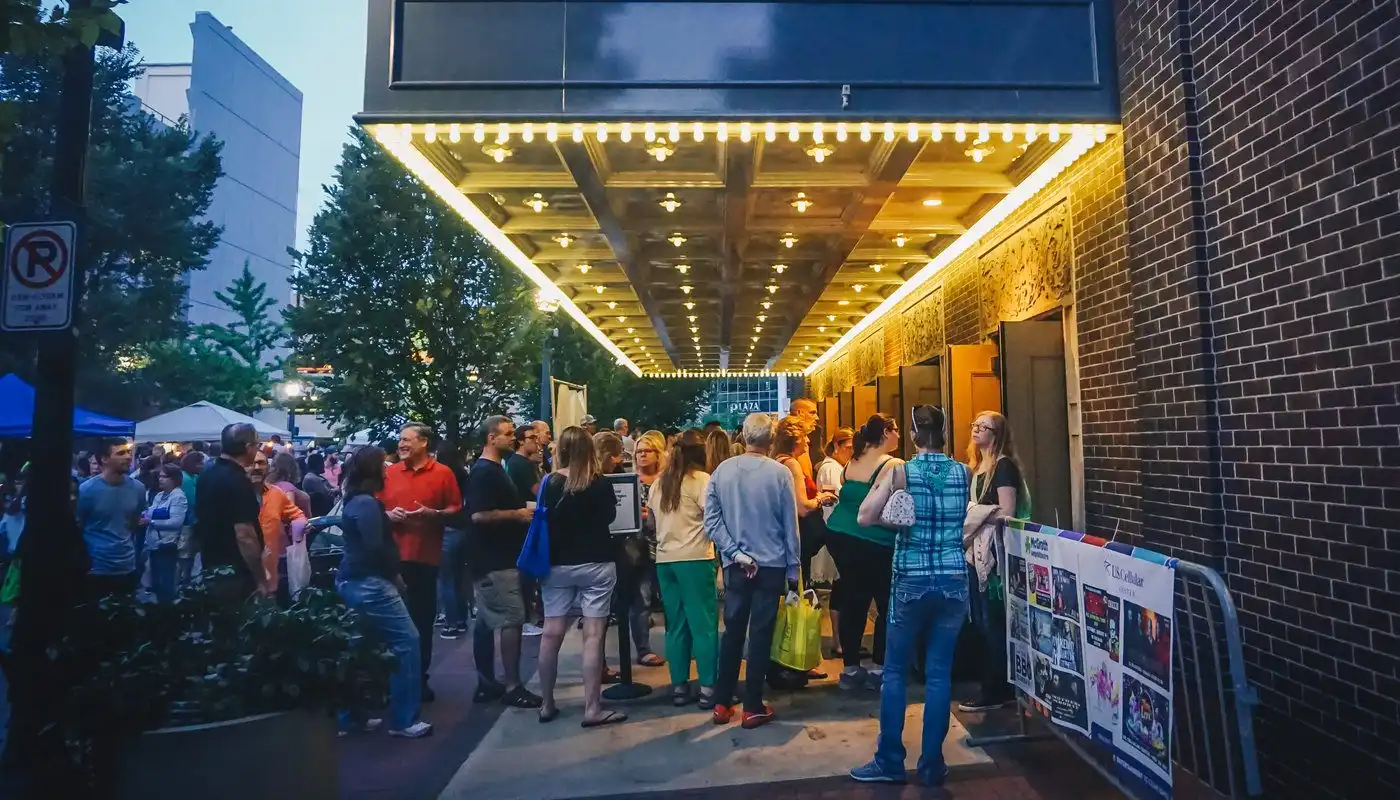 People stand below lights at dusk