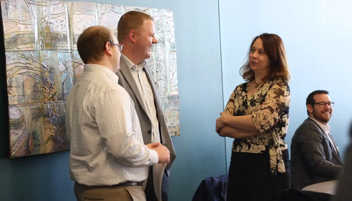 Three people discuss items at a business luncheon