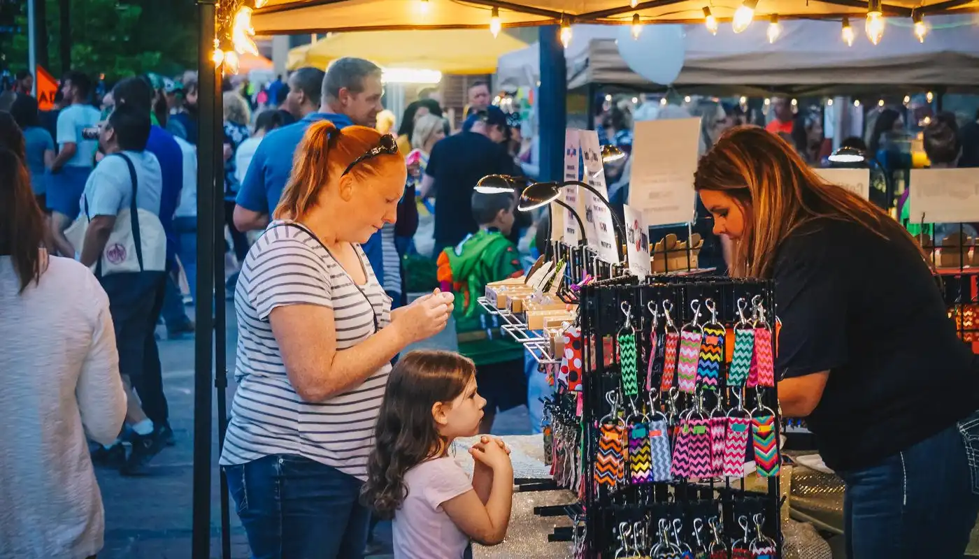 A patron purchases an item from a vendor stall at the Cedar Rapids Market After Dark