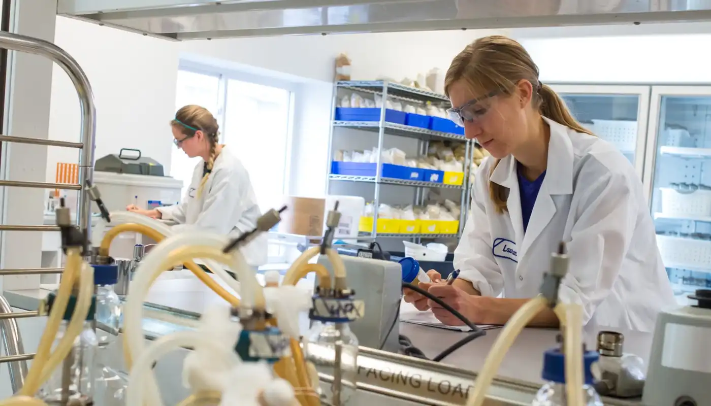 A young woman works with technical instruments in a laboratory setting