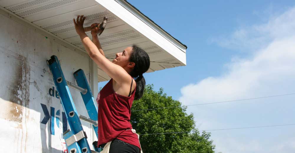 A volunteer repairs a house