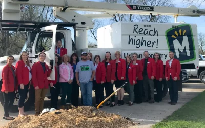 A group in red jackets stand in front of a work truck