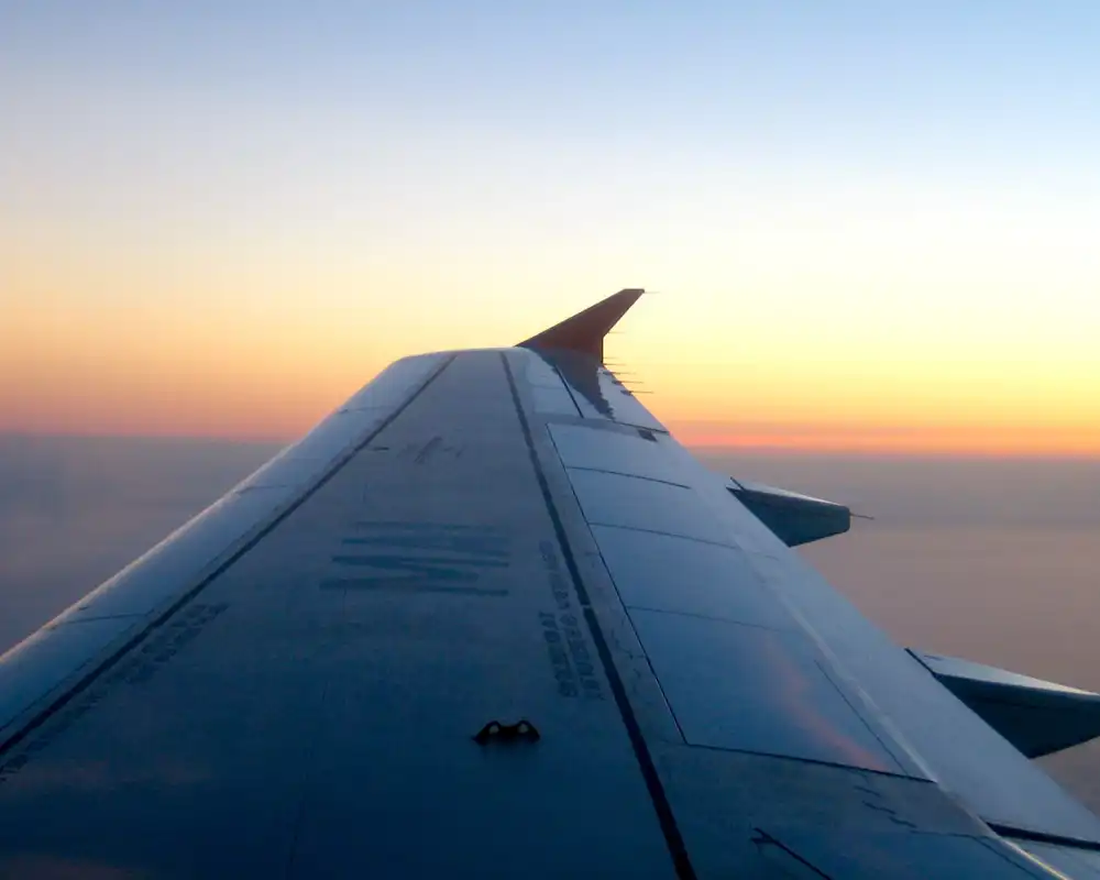 An airplane wing as it soars over the clouds