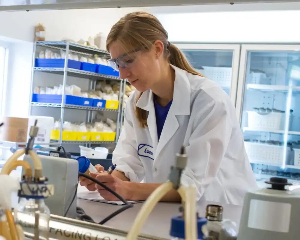 A young woman works in a bio lab with lab coat and beakers