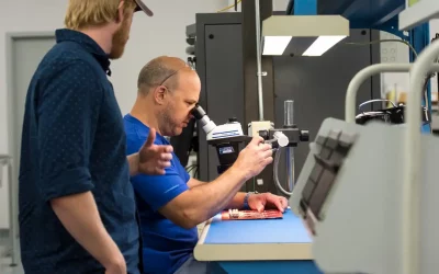 Two people work and look through a microscope