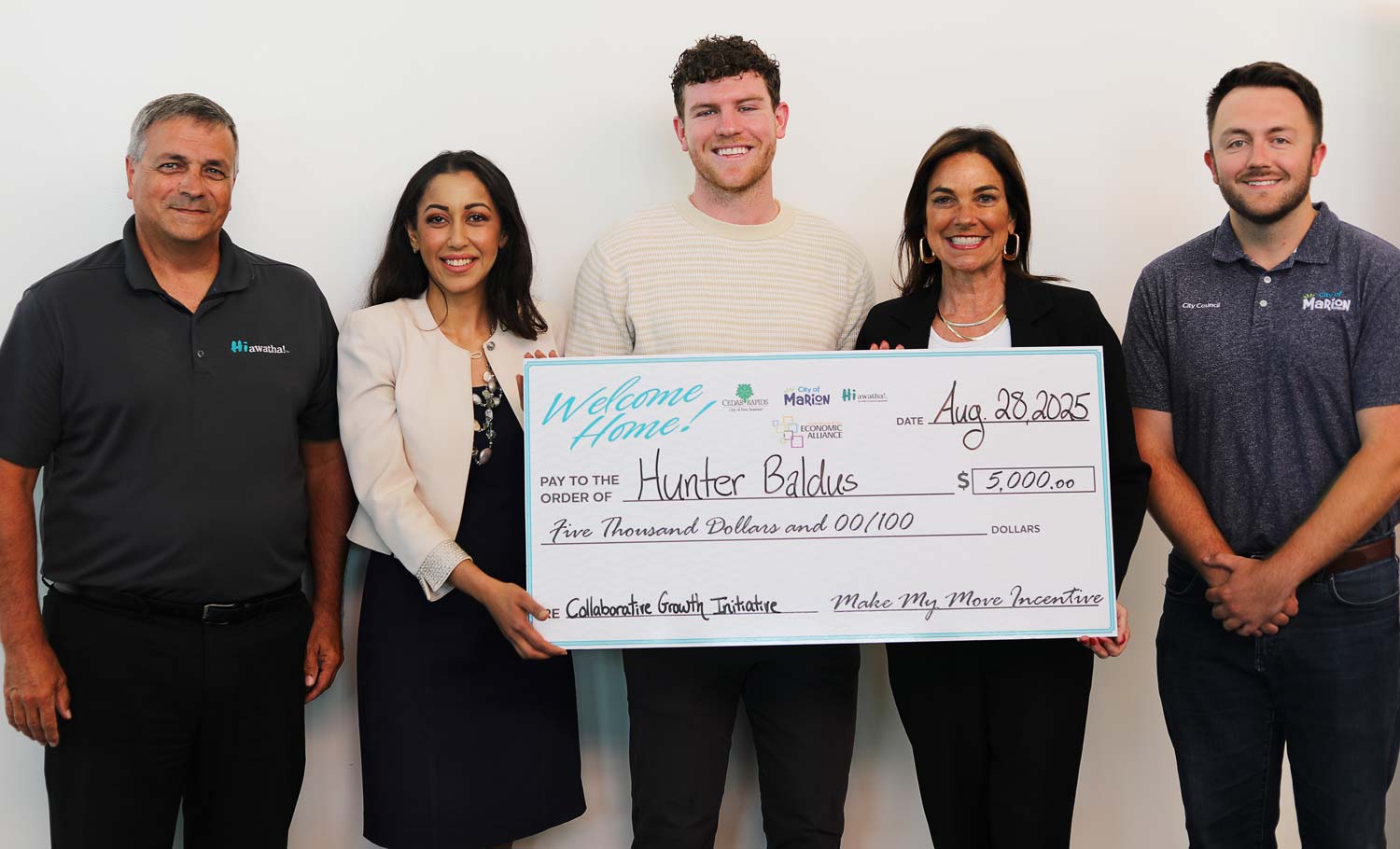 Make My Move Mover, Hunter Baldus, accepts his incentives with representatives from Cedar Rapids Metro Economic Alliance, City of Hiawatha, City of Cedar Rapids, and City of Marion.